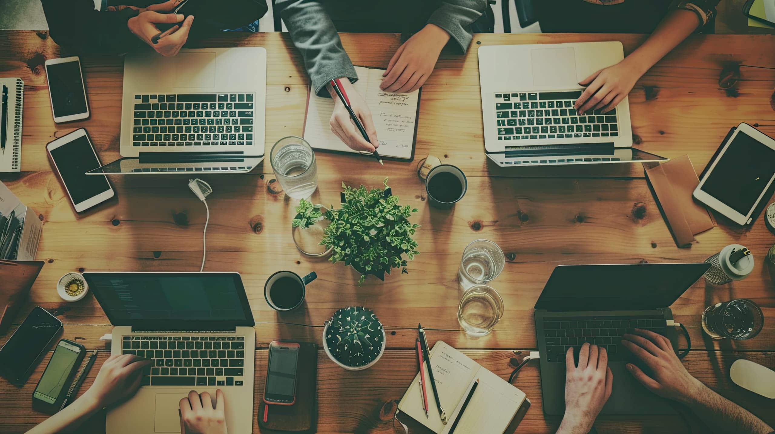 uma equipe de pessoas de diferentes áreas e origens reunida ao redor de uma mesa, discutindo estratégias para um projeto social, simbolizando a colaboração entre várias disciplinas para alcançar um objetivo comum.